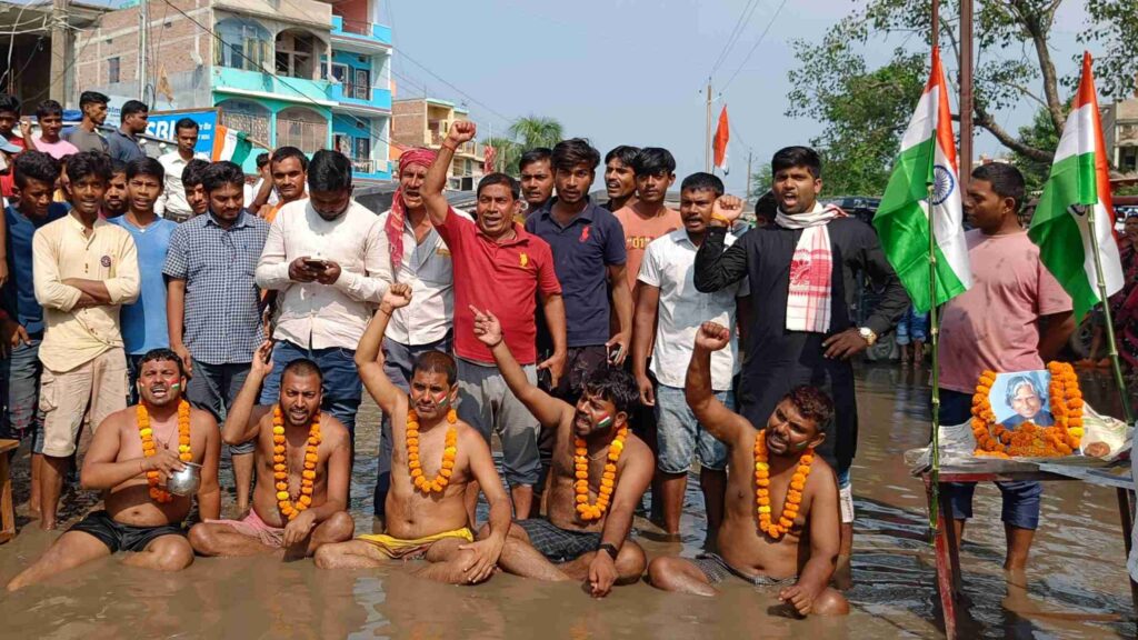 समस्तीपुर: NH-122 B की दुर्दशा देख लिजिए सरकार, 3 दिनों से बीच सड़क पर जमे पानी में बैठे प्रदर्शनकारियों ने नित्यानंद राय को दे डाली चेतावनी... 1 Picsart 22 10 15 19 00 21 414